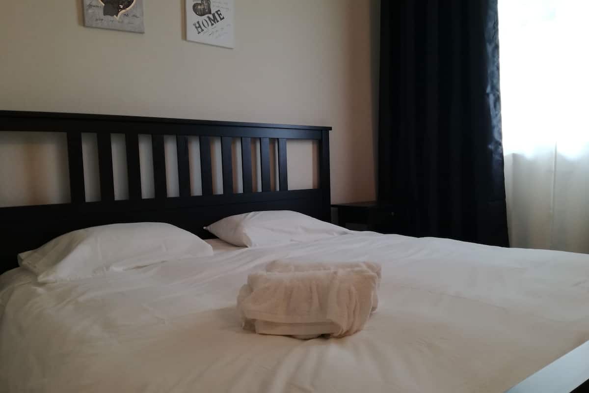 Una cama bien hecha con sábanas blancas y una toalla doblada en el centro.