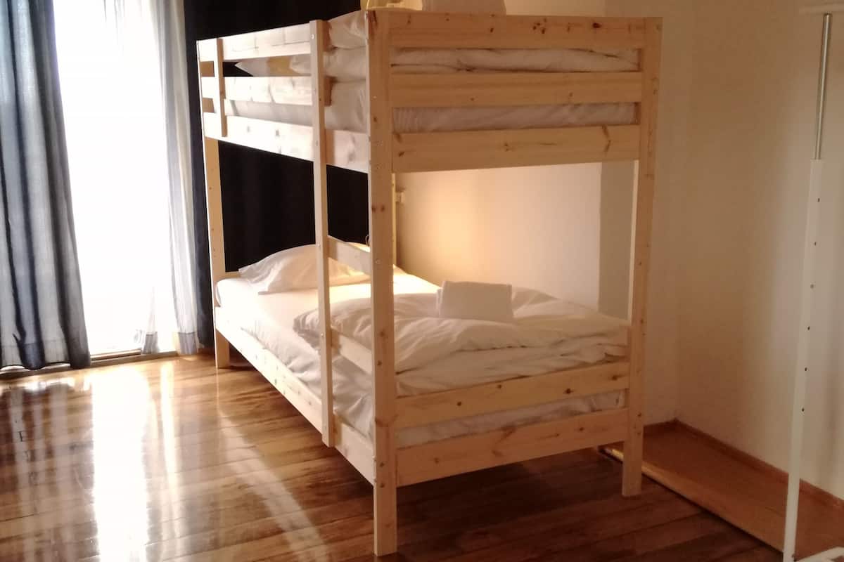 Una cama tipo litera en una habitación con pisos de madera y techo inclinado.