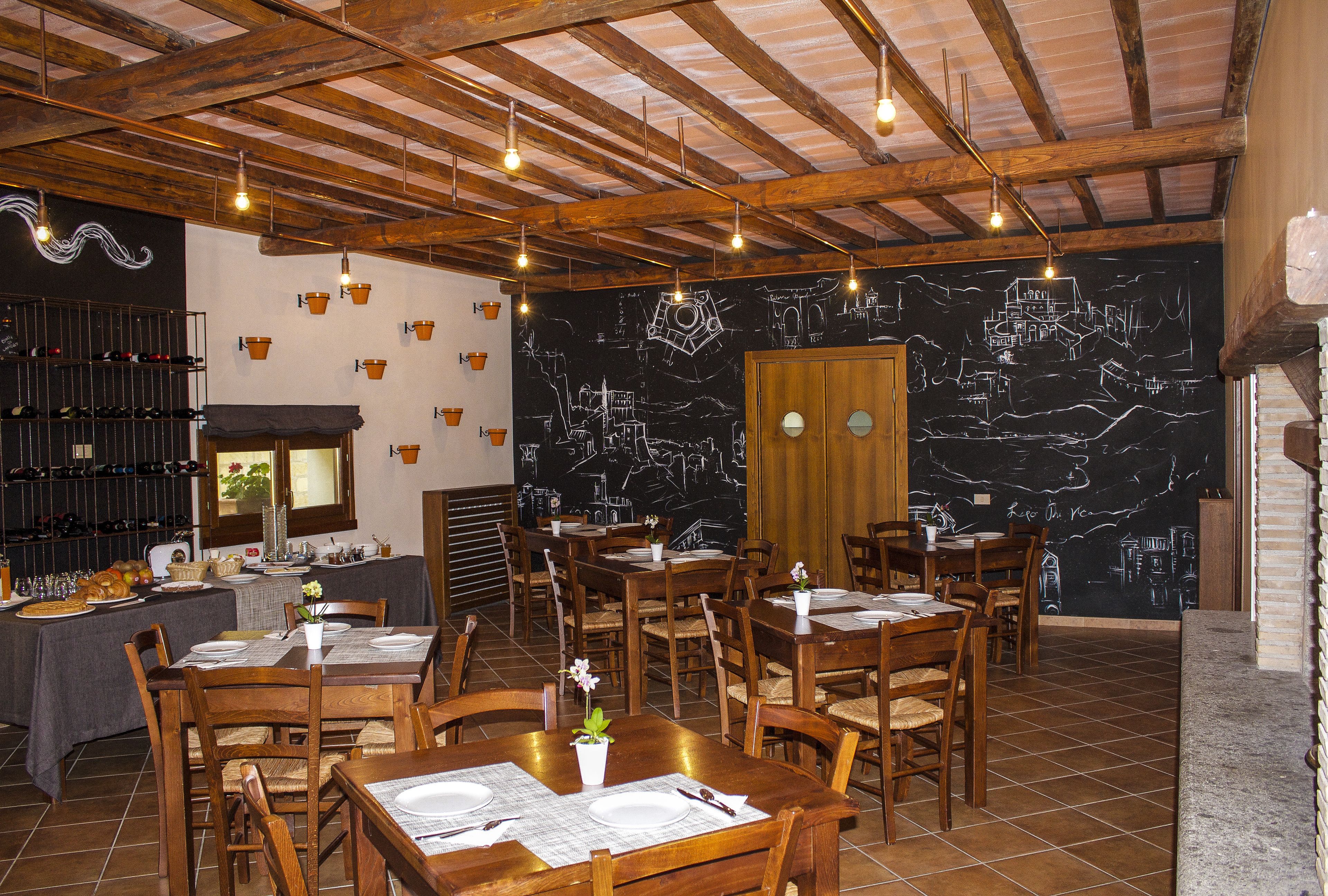 A restaurant with wooden tables and chairs, a chalkboard wall with drawings, and a wine rack with bottles.