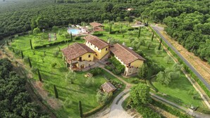 Una amplia villa con varias construcciones, piscina y jardines bien cuidados.