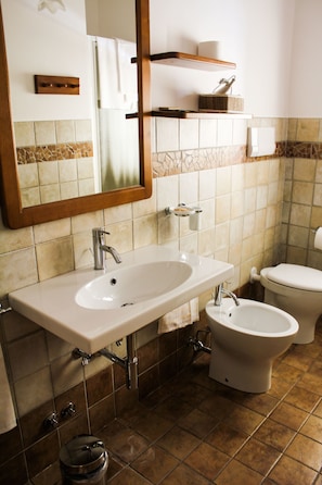 Un baño con lavamanos, espejo, inodoro y bidé.