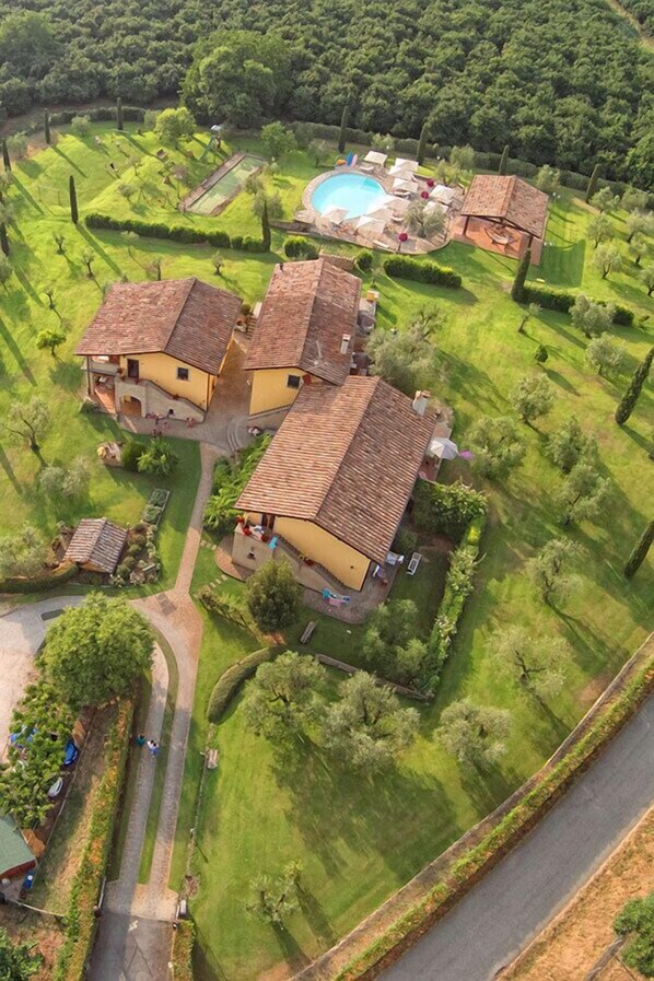 An aerial view of a property with multiple buildings, a swimming pool, and well-maintained gardens.