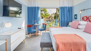Habitación de hotel con cama, escritorio, silla, una mesita y vistas al exterior.