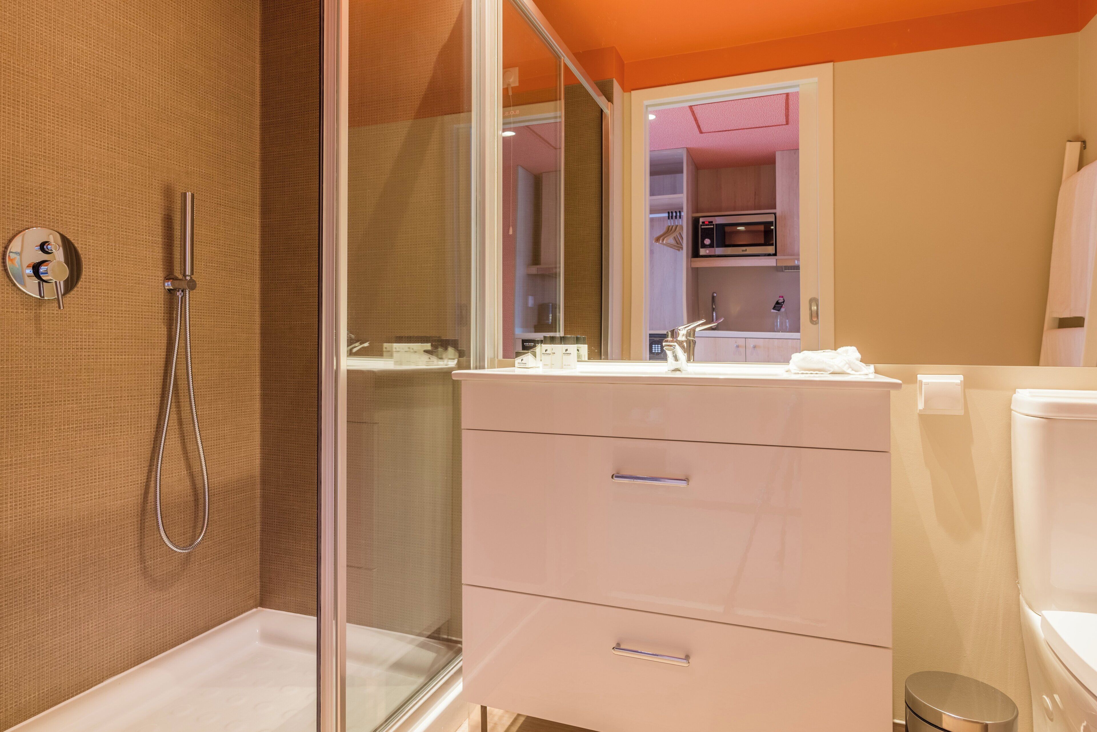 A bathroom with a shower, a sink, a mirror, and a toilet.