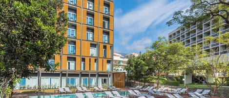 A hotel with a rooftop pool area, multiple balconies, and a modern architectural design.
