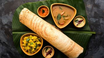 Una comida tradicional del sur de la India con dosa, sambar y chutney de coco, presentada sobre hoja de plátano.