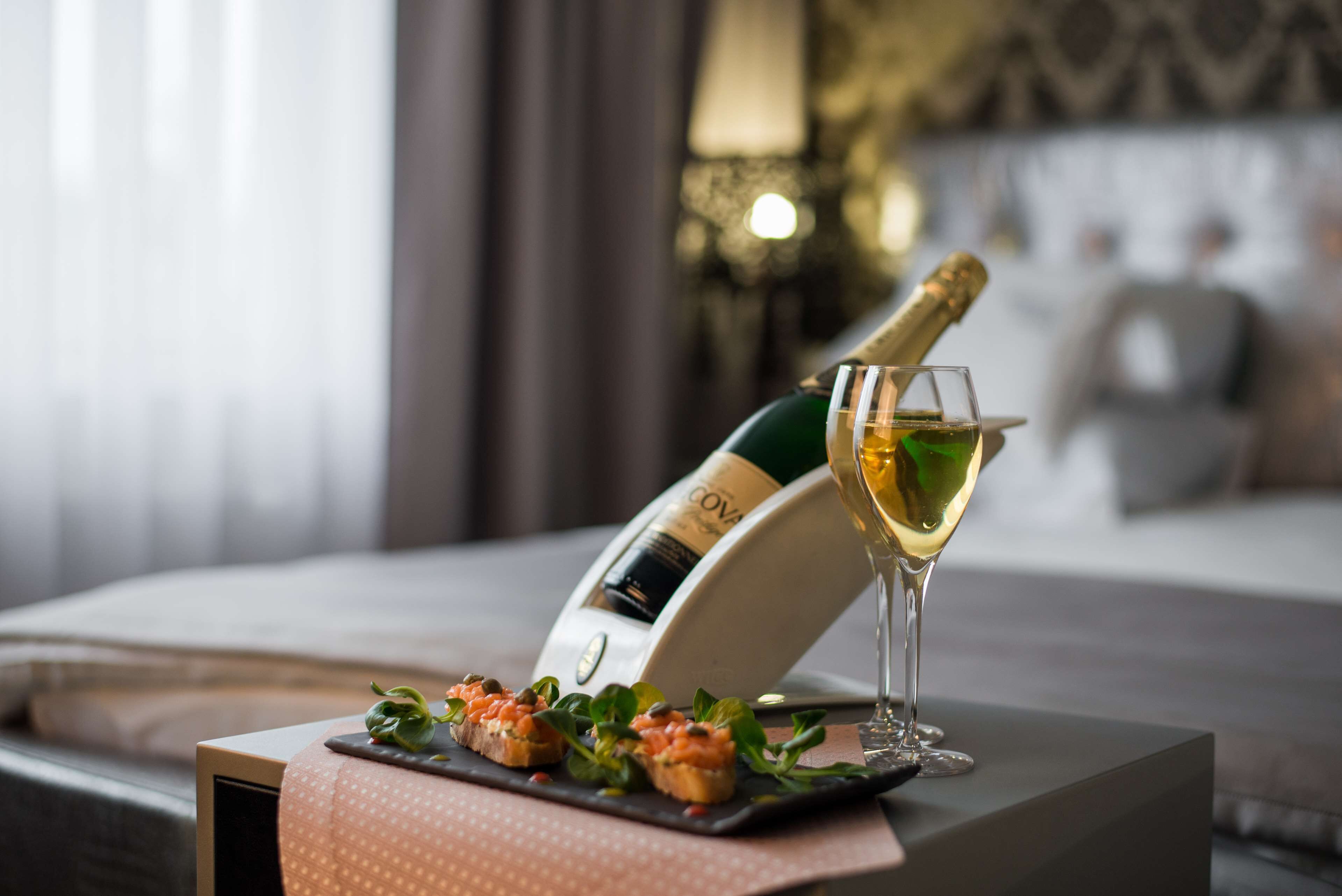 Una botella de champán y una copa sobre una mesa con un plato de aperitivos.