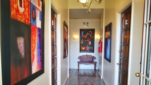 A hallway with a patterned floor, a bench, and artwork on the walls. - Hotel Casa 69 (San José)