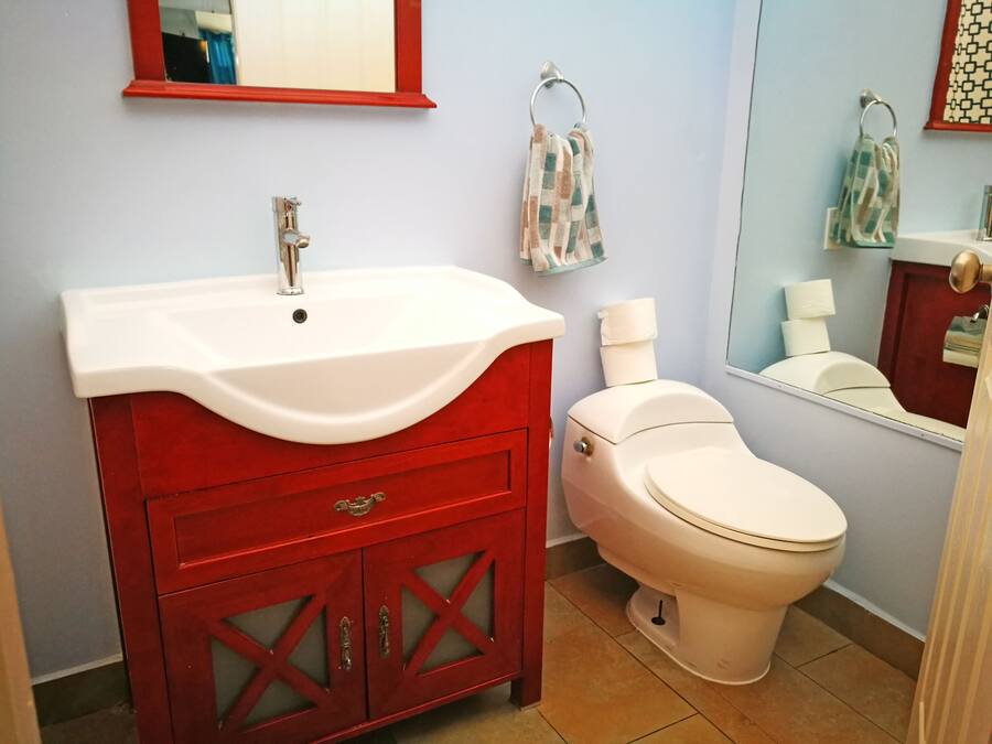 A bathroom with a white sink, red vanity, and a white toilet.