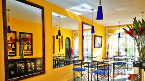 A bright yellow interior with mirrored walls, blue hanging lights, and a tiled floor. - Hotel Casa 69 (San José)