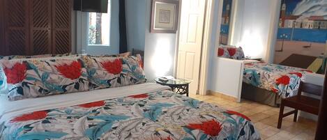 Un dormitorio con dos camas, un televisor, una mesita y una puerta que da a otra habitación.
