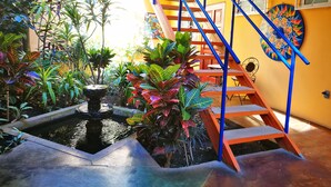 A staircase with blue railings leading to a second floor, surrounded by lush tropical plants and a small water feature. - Hotel Casa 69 (San José)