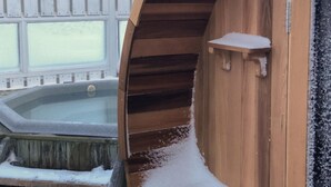 A wooden spa tub with a window, a wooden deck, and string lights. - Hotel Lækur (Rangárþing ytra)