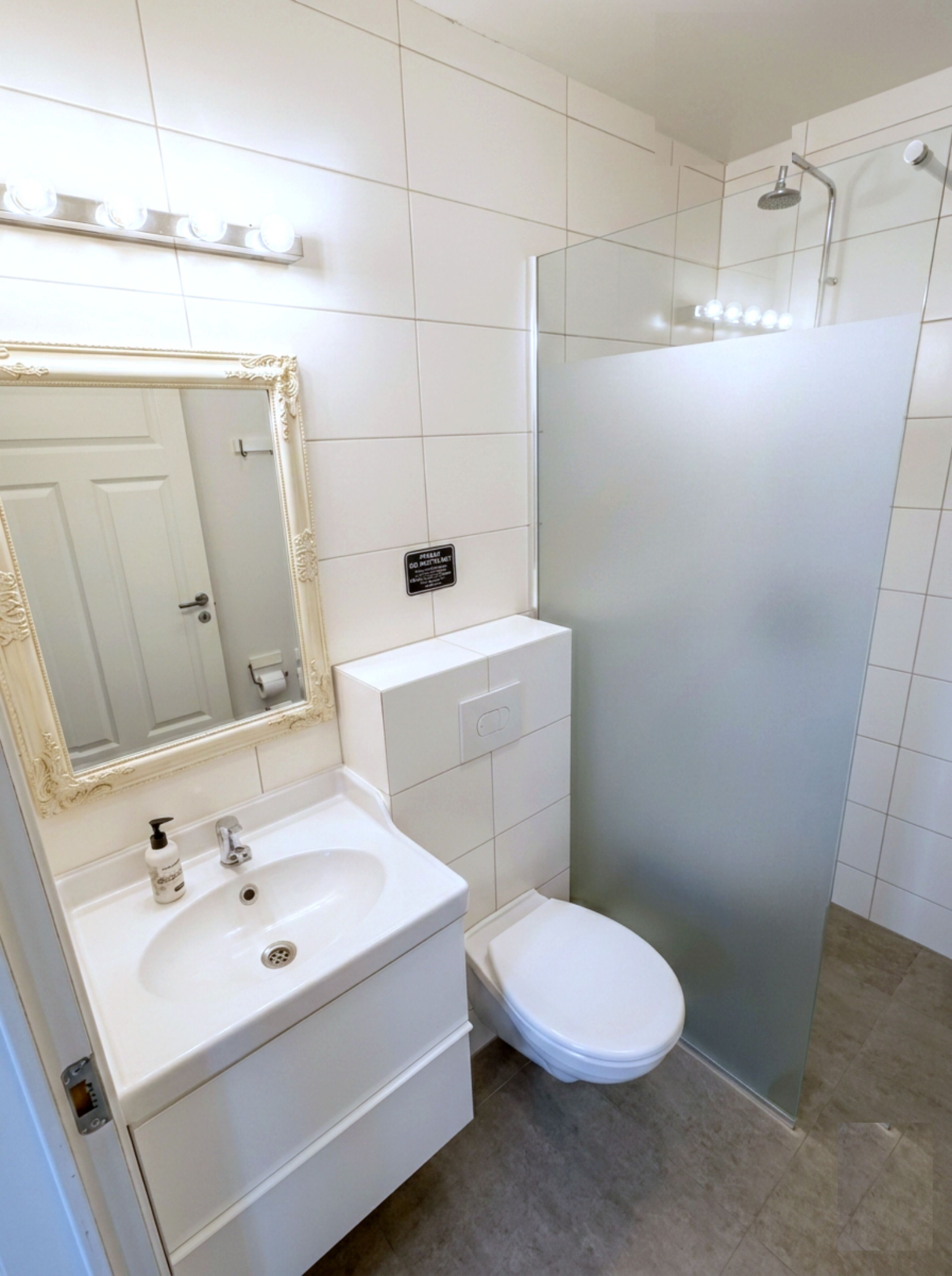 A bathroom with a white sink, mirror, toilet, and shower.