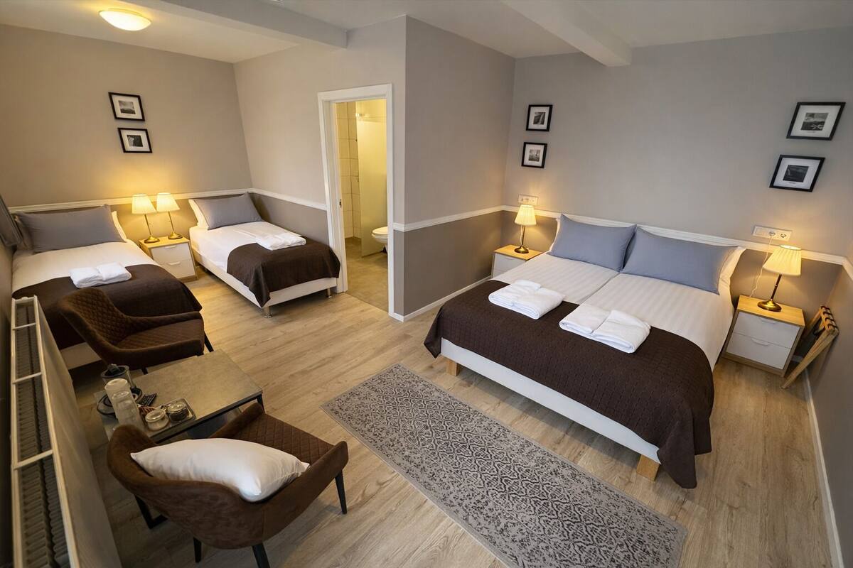 A hotel room with a bed, two bedside tables with lamps, a chair, a small table with a tray, and a patterned rug.