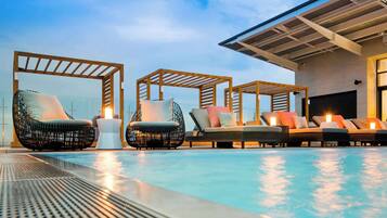 Relax by the serene pool surrounded by comfortable seating and a shaded pergola.