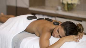 A person receiving a back massage with heated stones.