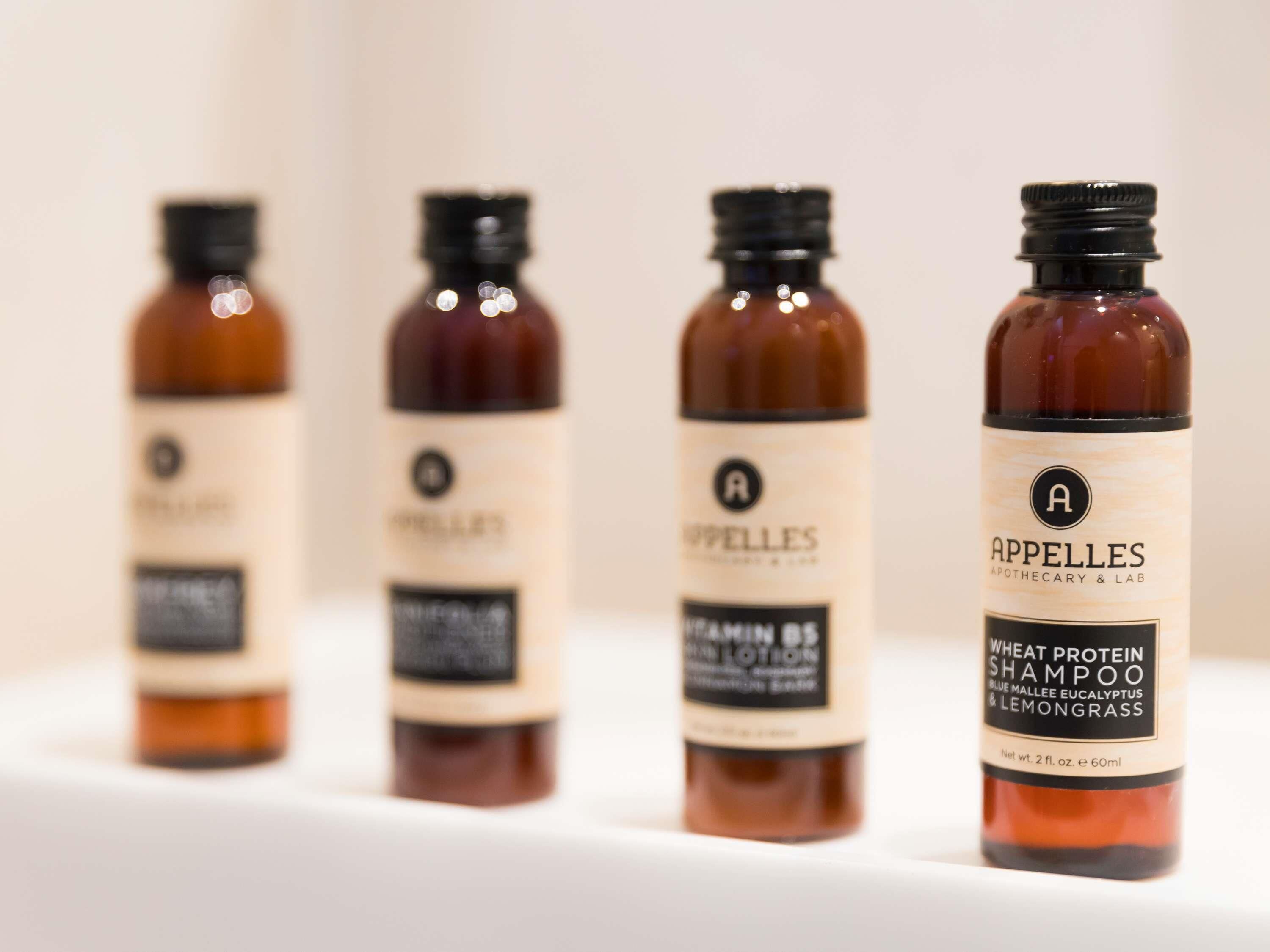 Four bottles of hair care products with labels, arranged on a white surface.