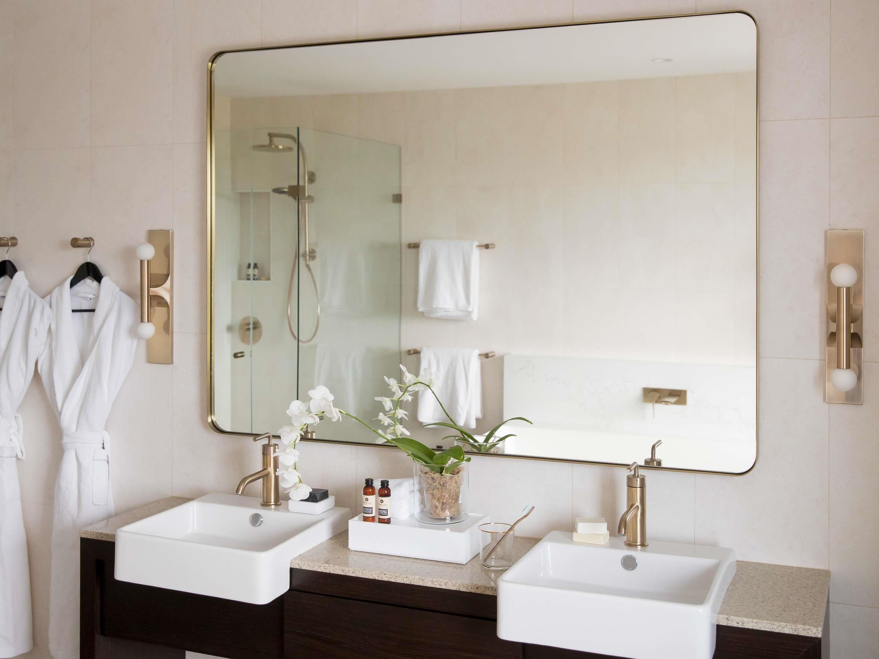 A bathroom with two sinks, a large mirror, and a shower.