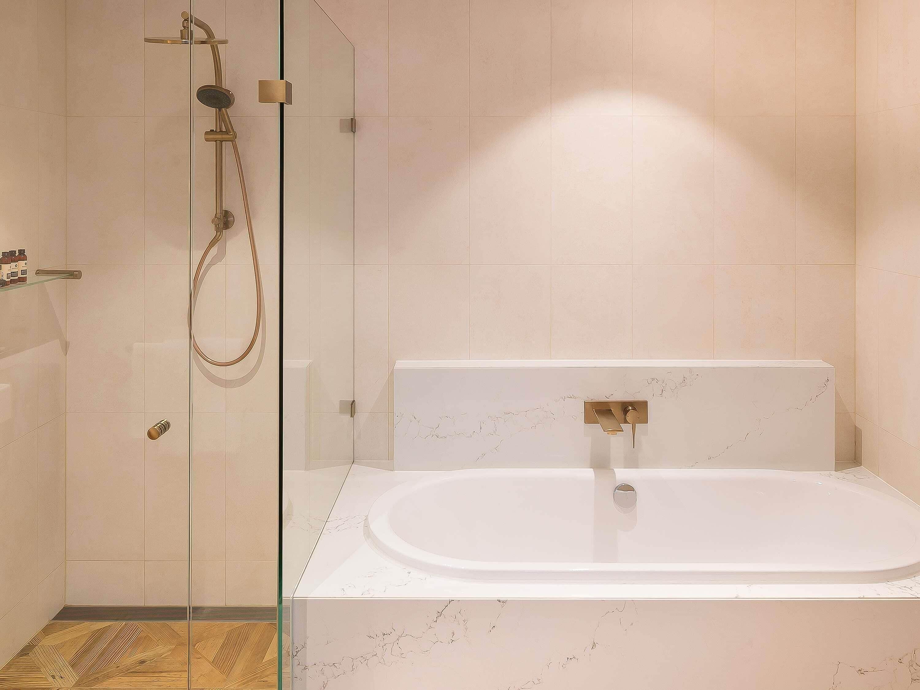 A modern bathroom with a glass-enclosed shower, a freestanding bathtub, and a marble-tiled wall.