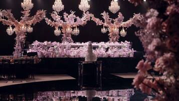 A grand hall with chandeliers, a tiered floral arrangement, and a reflective water feature.