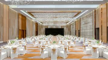 A banquet hall with round tables, white tablecloths, and gold sashes.