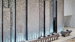 Un intérieur moderne avec un mur réfléchissant, un banc et un sol en marbre.