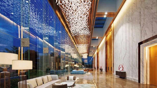 Un hall d’entrée moderne avec un mur en verre, un canapé, des fauteuils et un tapis à motifs.