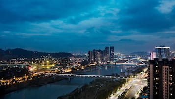 Eine nächtliche Stadtansicht mit einem Fluss, einer Brücke und Hochhäusern.