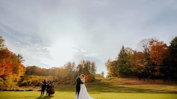 A wedding ceremony on a grassy field with trees in the background.