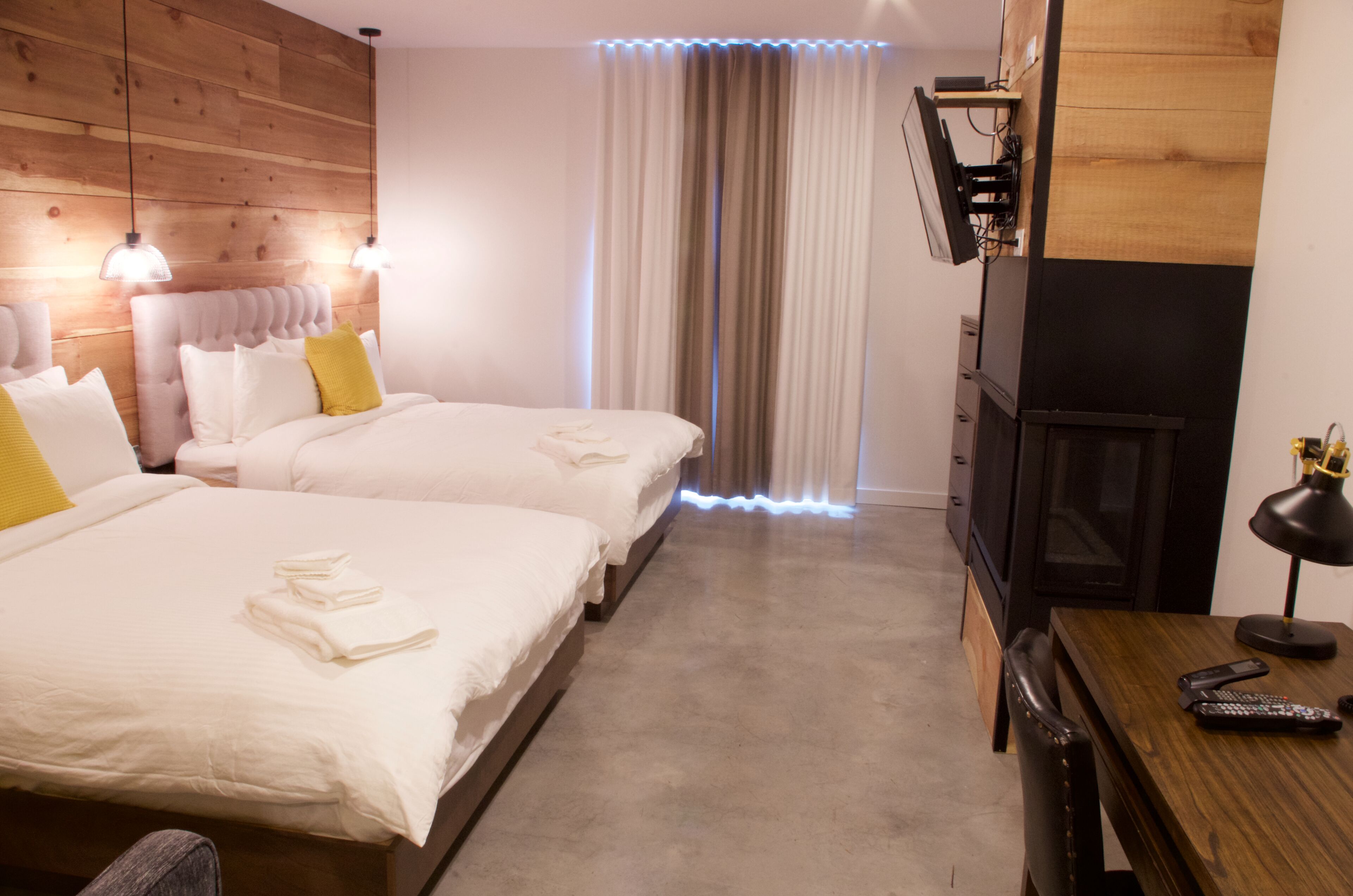 Habitación de hotel con dos camas, un escritorio, una silla, un televisor y una lámpara.