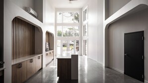 A spacious hallway with a wooden cabinet, a black door, and a large window providing natural light. - Rawdon Golf Resort (Rawdon)