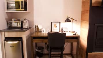A compact kitchen with a microwave, toaster, kettle, and a refrigerator.