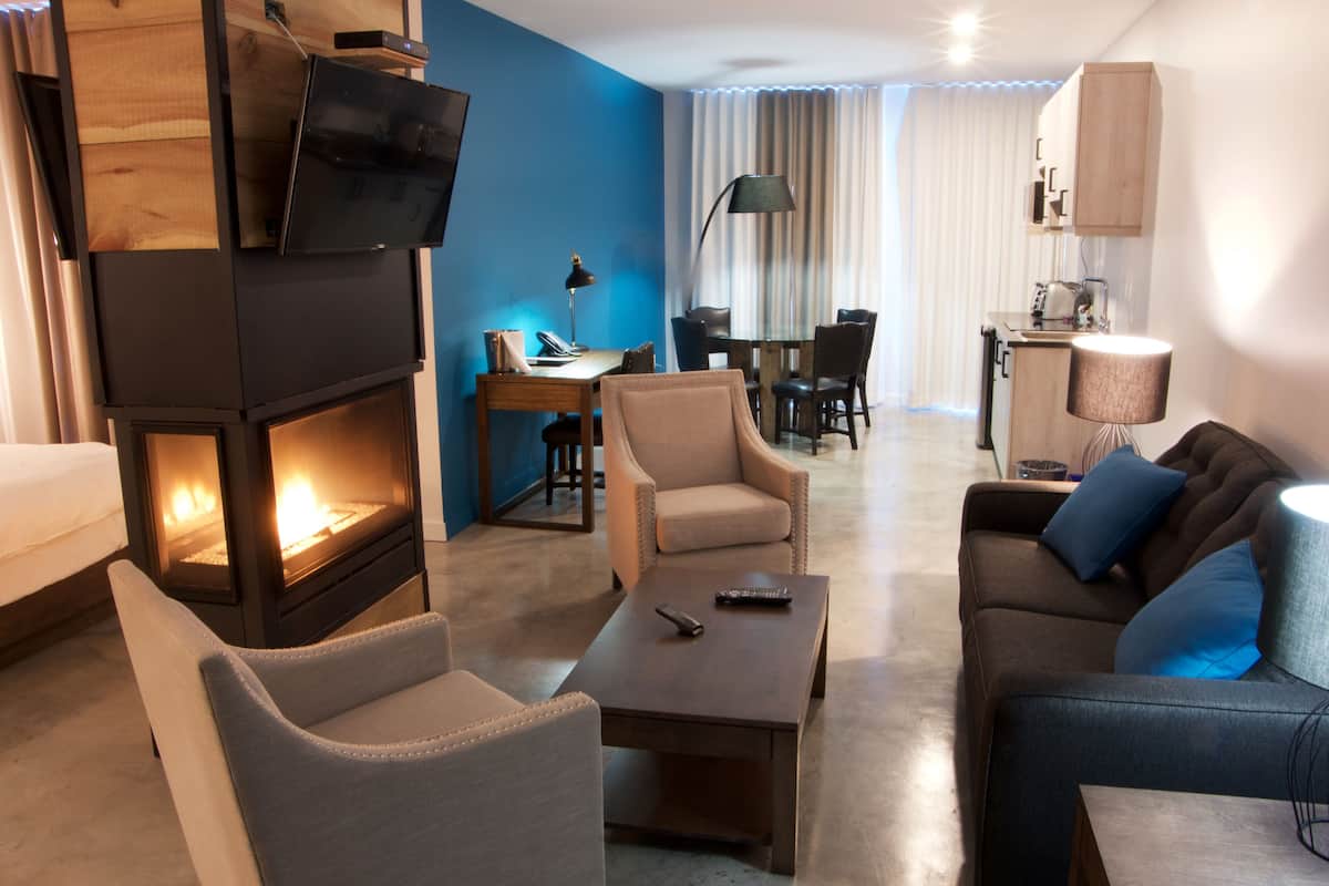 Una sala de estar moderna con chimenea, asientos cómodos, zona de comedor y una kitchenette.