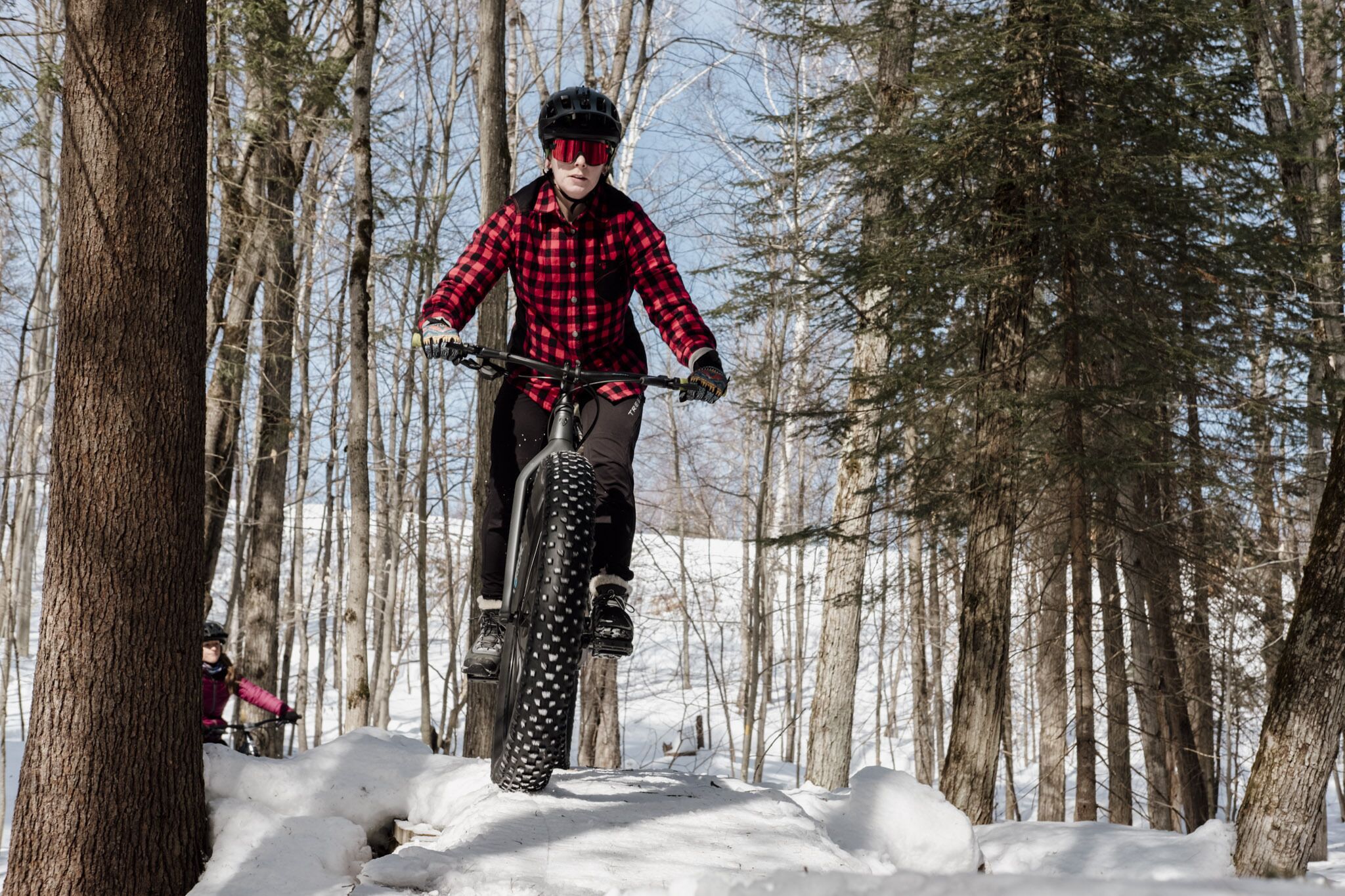 Une personne qui fait du vélo sur la neige dans une forêt enneigée.