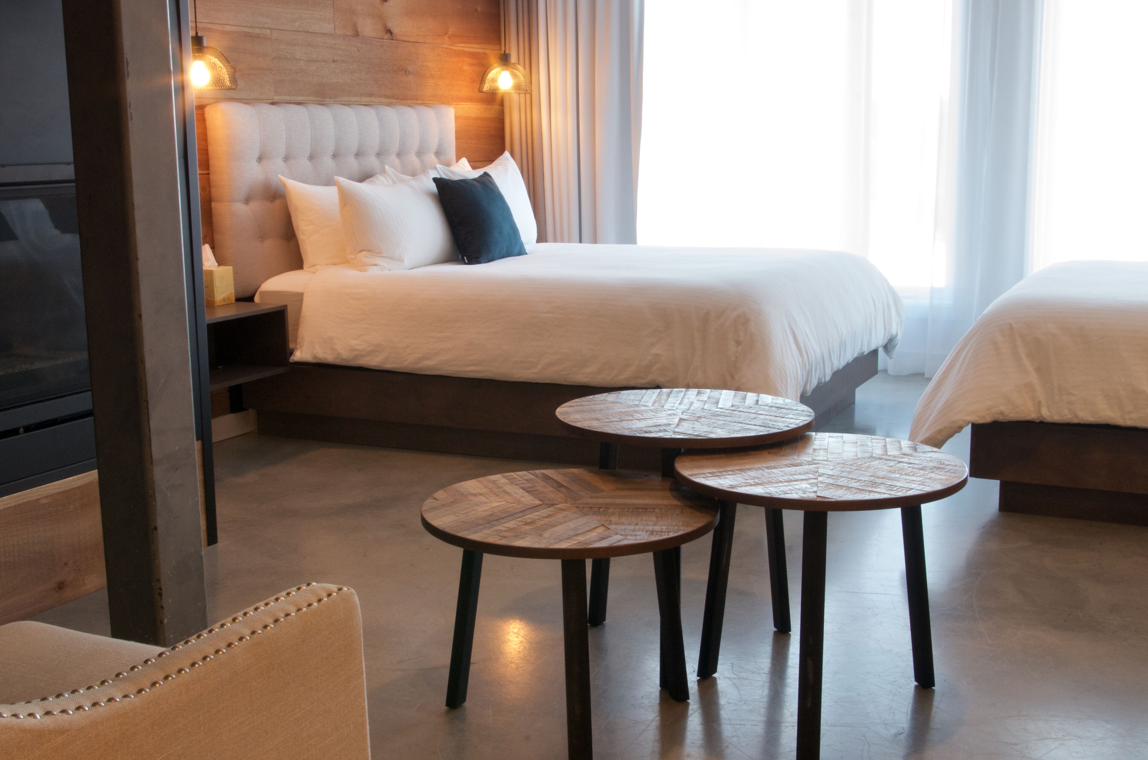 Een hotelkamer met een groot bed, twee nachtkastjes, een stoel en een houten hoofdeinde.