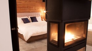 A bedroom with a bed, a wooden headboard, and a wood-burning stove. - Rawdon Golf Resort (Rawdon)