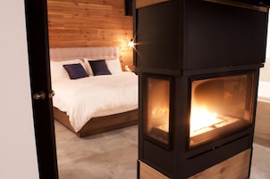 Un dormitorio con una cama, cabecera de madera y un estufa de leña.