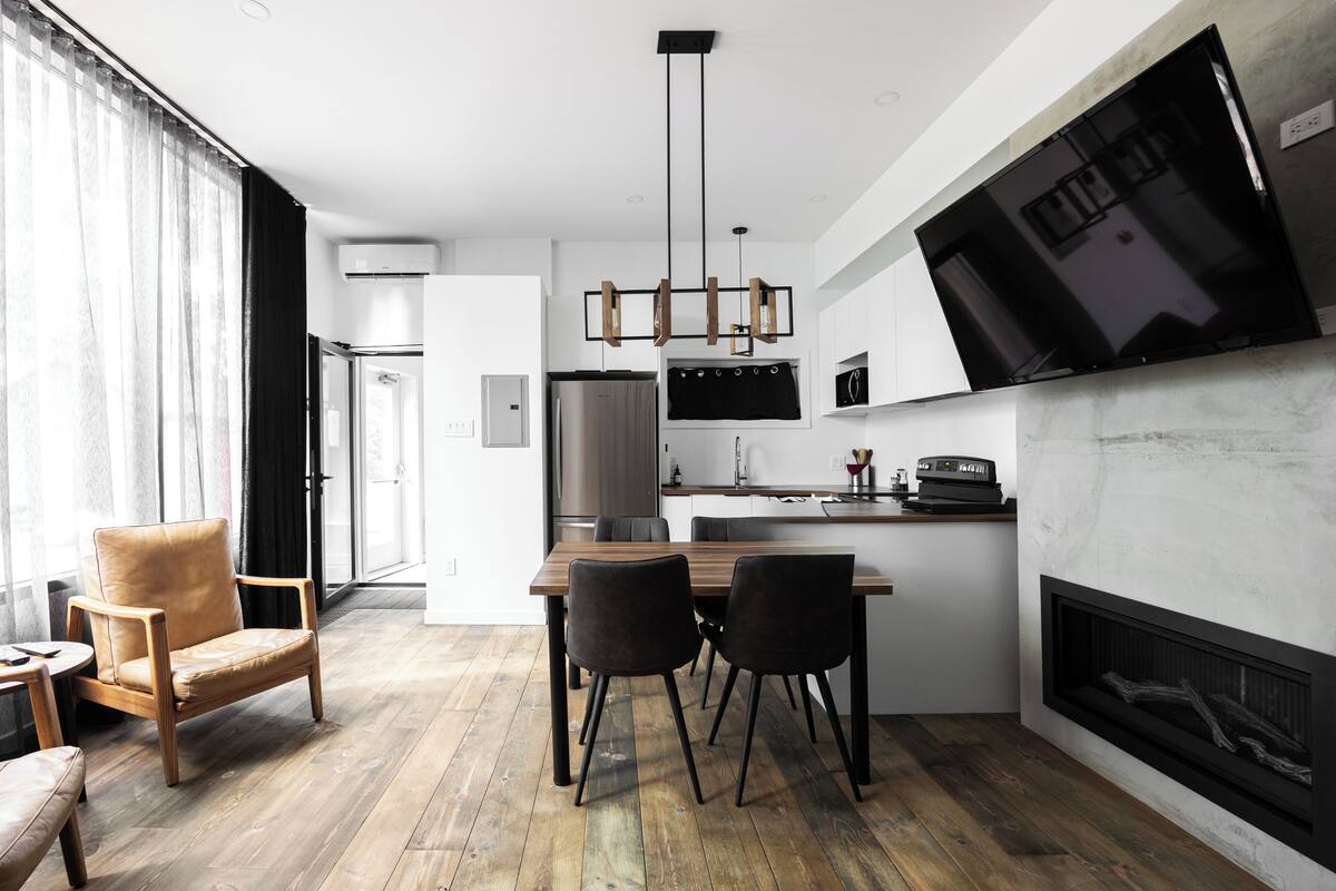 Una cocina moderna con comedor, chimenea y televisor grande.