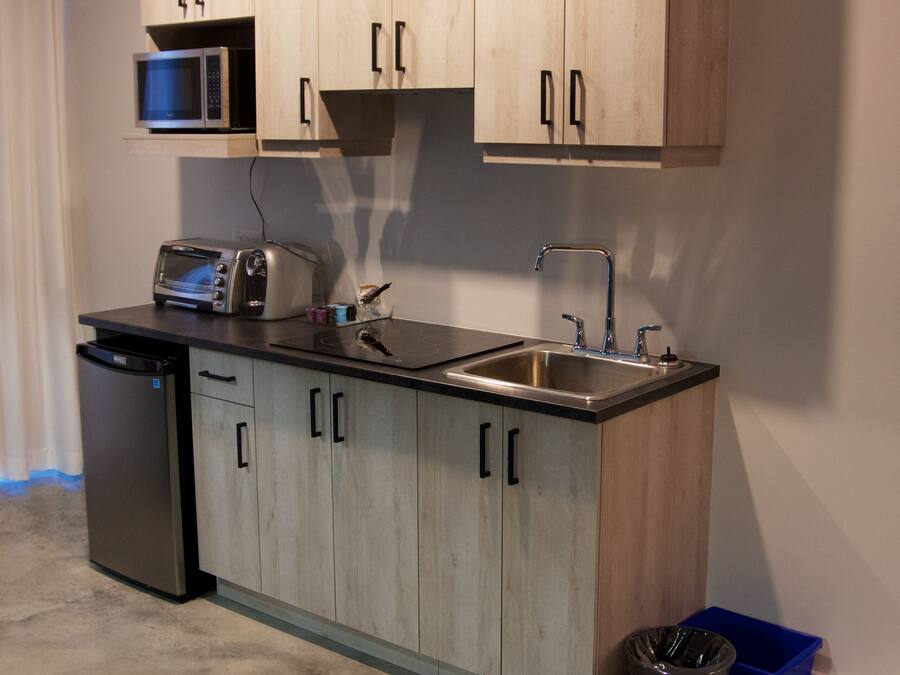 A compact kitchen with wooden cabinets, a microwave, a toaster, a sink, and a dishwasher.