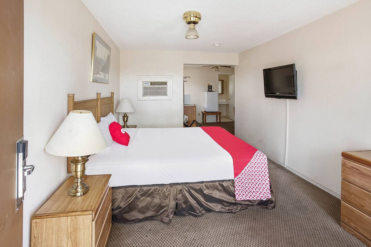 Une chambre d’hôtel avec un lit, une télévision, une lampe et une commode.