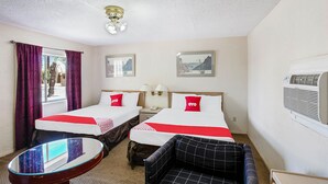 Ein Hotelzimmer mit zwei Betten, einem kleinen Tisch, einem Stuhl und einer Klimaanlage.