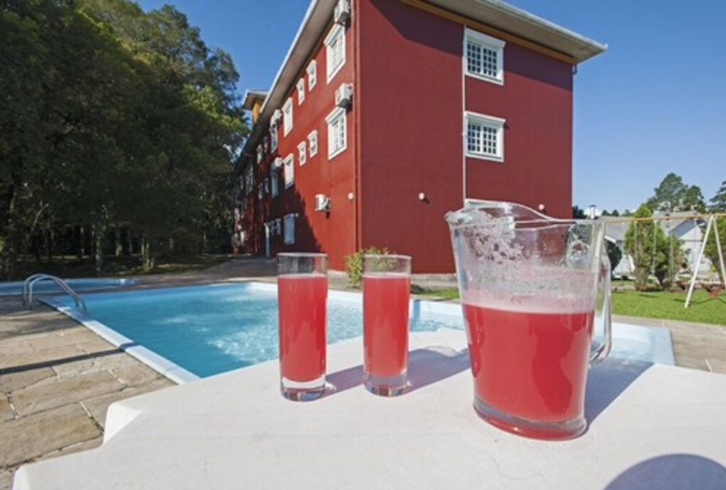 Piscina com um edifício vermelho ao fundo.