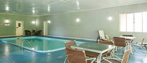 A swimming pool area with lounge chairs and tables, a door, and a window.