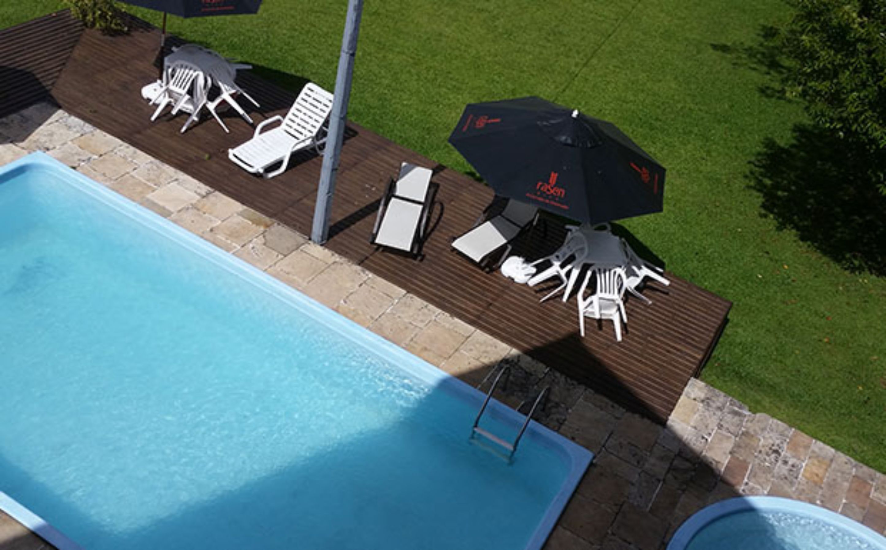 A swimming pool with lounge chairs and umbrellas on a wooden deck.