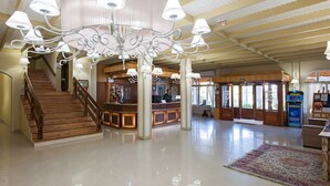 A spacious lobby with a grand chandelier, a wooden staircase, and a reception desk. - Hotel Galo Vermelho (Gramado)