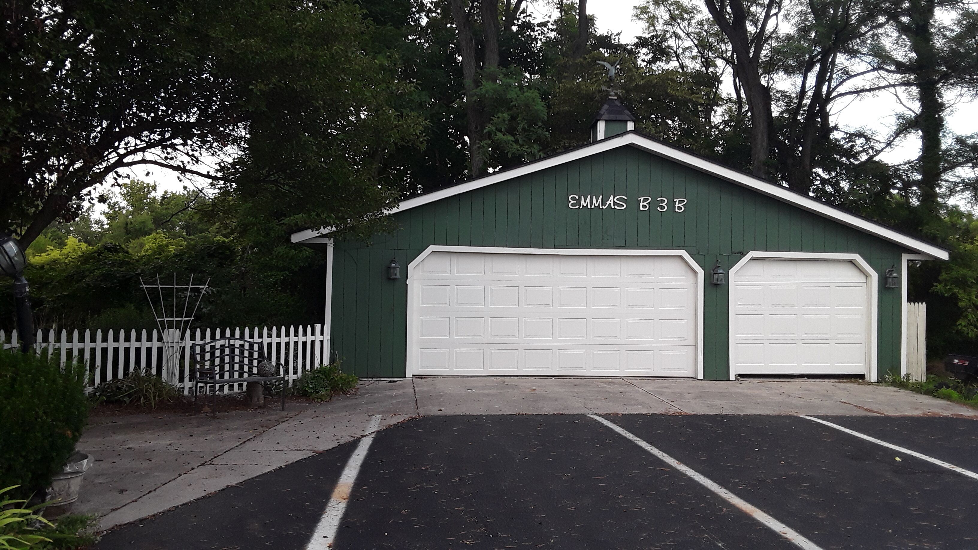 A green building with two white garage doors and a sign reading "EMMAS B3B".