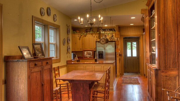 A spacious kitchen with wooden cabinets, a central island, and a dining table with chairs. - Emma's Bed and Breakfast (Springfield)