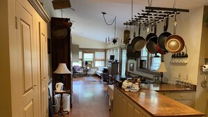 A spacious kitchen with wooden floors, a central island, and a variety of hanging pots and pans. - Emma's Bed and Breakfast (Springfield)