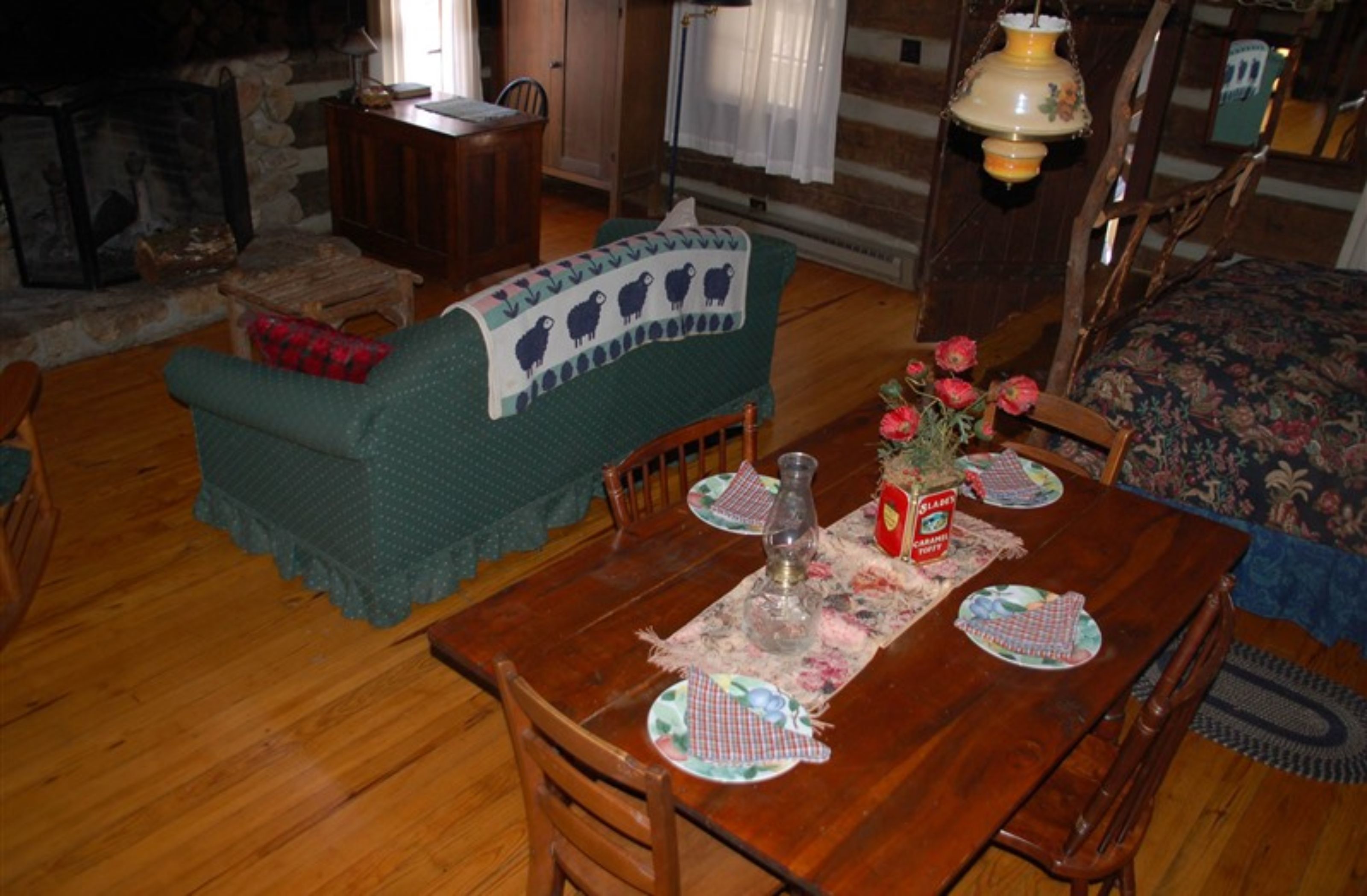 Ein gemütliches Wohnzimmer mit einem Holzesstisch, gedeckt für zwei Personen, einem grünen Sofa und einem Kamin.